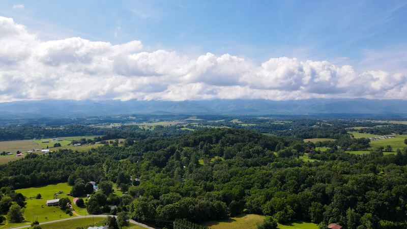 Aerial view across rolling farmland toward the mountains