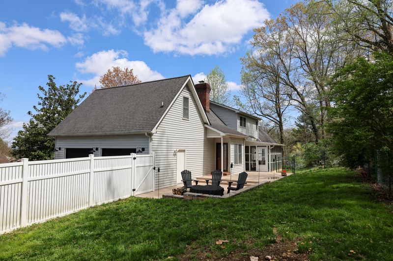 Back of the home with a white fence and patio seating