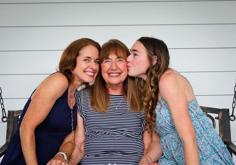 Three generations of women laughing together on a porch swing